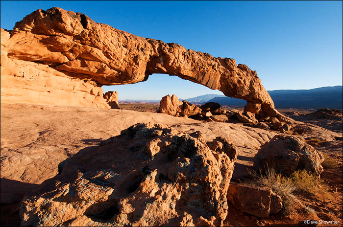 The last warm rays of a winter afternoon light Sunset Arch before the sun disappears behind the Straight Cliffs. The arch is...